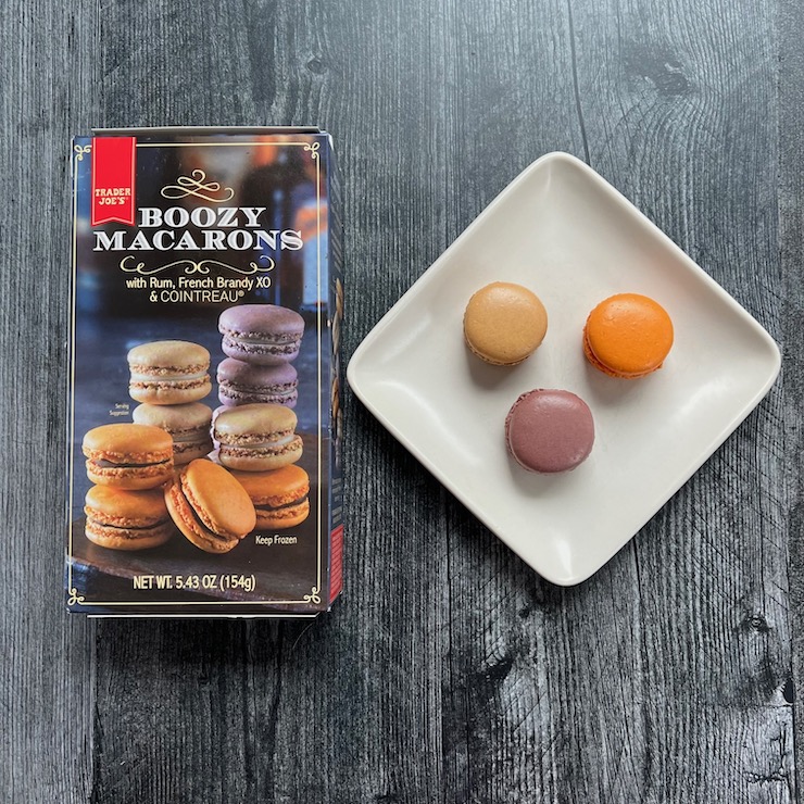 Three macarons on a white plate next to the Trader joe's Box of macaons.