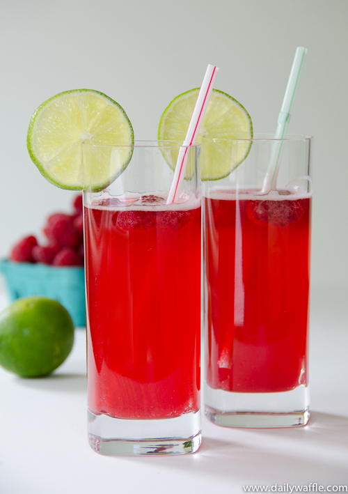 Two glasses of raspberry spritzer with lime slices.