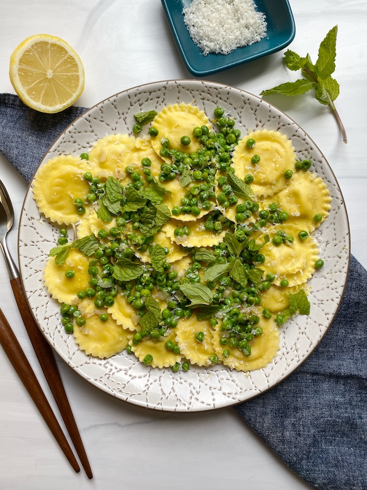 lemon ricotta ravioli with peas and mint on a white plate