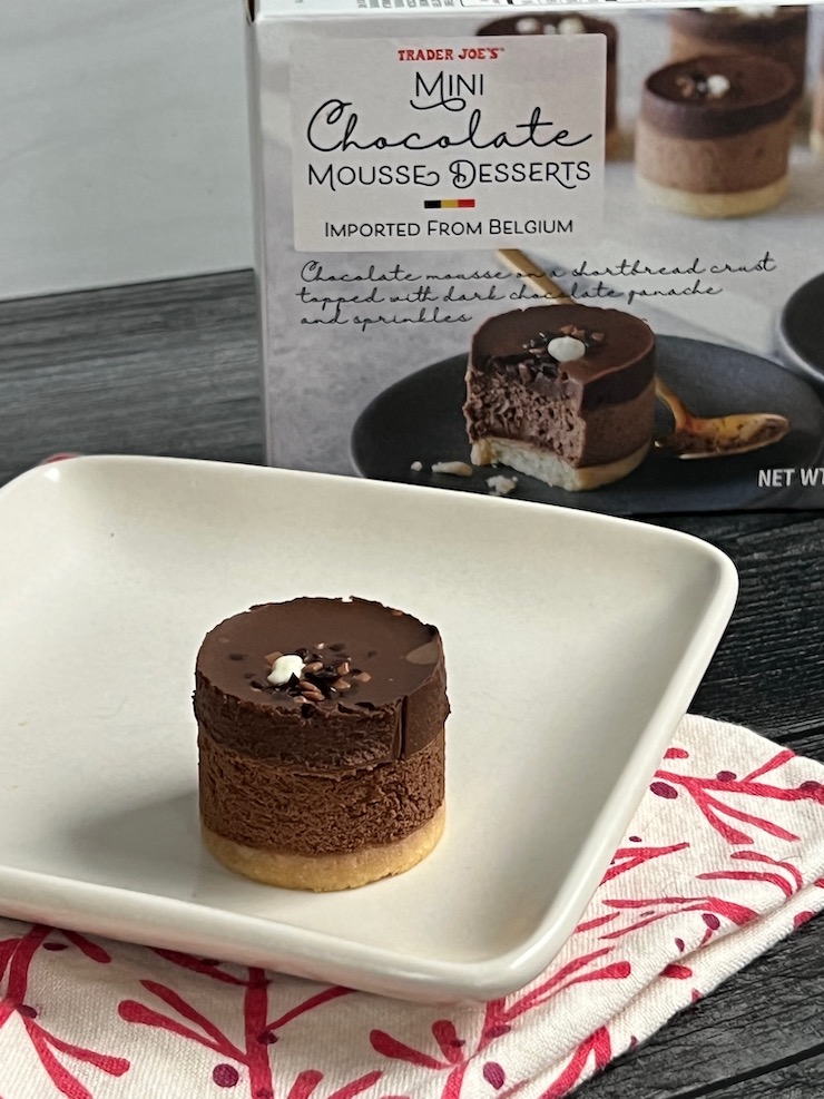 Trader Joe's Mini Chocolate Mousse Desserts box in the background of a single mini mousse served on a square white plate. 
