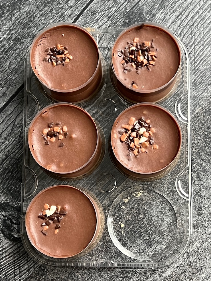 Six Trader Joe's mini chocolate mousse desserts unboxed, in their plastic tray on a weathered gray wood background.