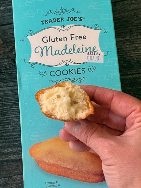 Trader JOe's Gluten Free Madeleines box. A hand holds half a madeleine showing the cross section.