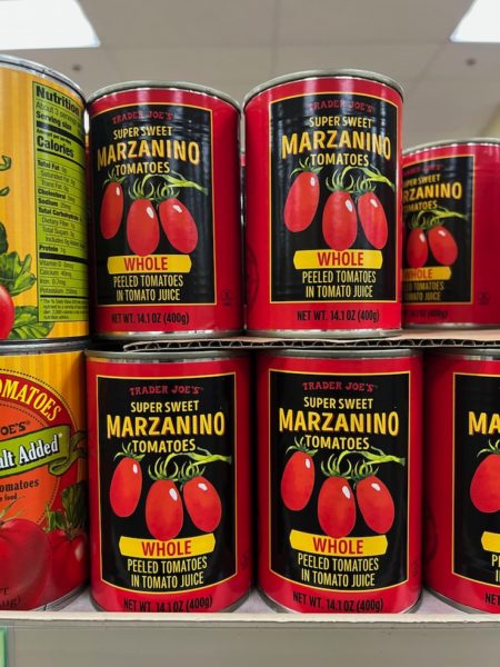 Cans of Trader Joe's Marzanino Tomatoes stacked on shelves in a Trader Joe's store. 