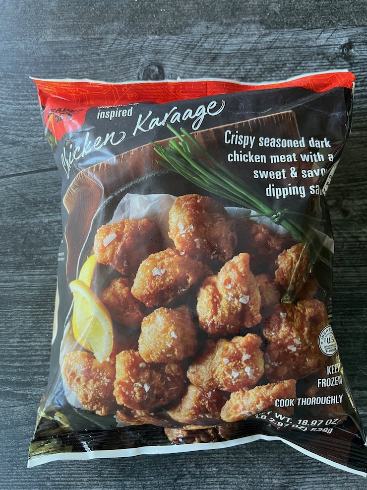 Bag of Trader Joe's Chicken Karaage  (crispy seasoned dark chicken menat with a sweet and savory dipping sauce) on a weathered wood background 