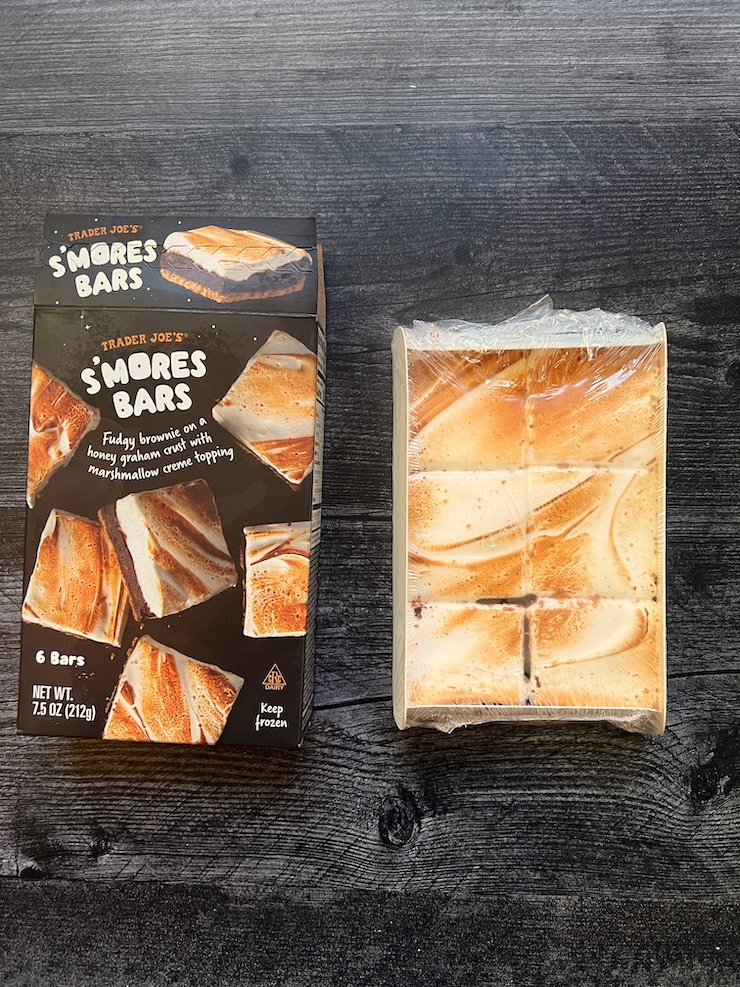 Trader Joe's Smores Bars box and its content side by side shown on a weathered wood background. 