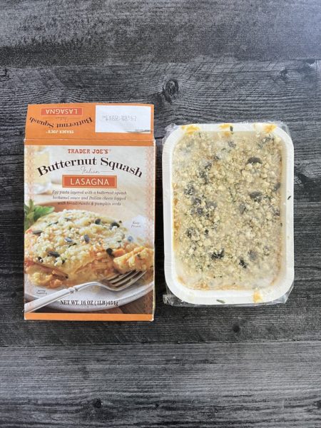 Trader Joe's Butternut Squash Lasagna box next to the actual uncooked lasagna, on a weathered wood background. 