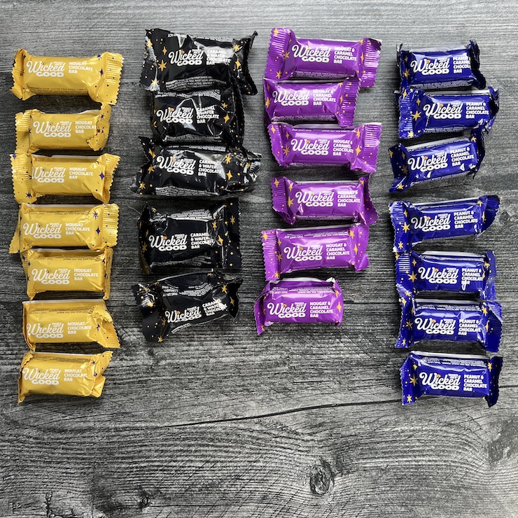 Individual bars from the Wicked Good Mini chocolate bars bag arranged to show the distribution of each flavor. On a weathered wood background. 