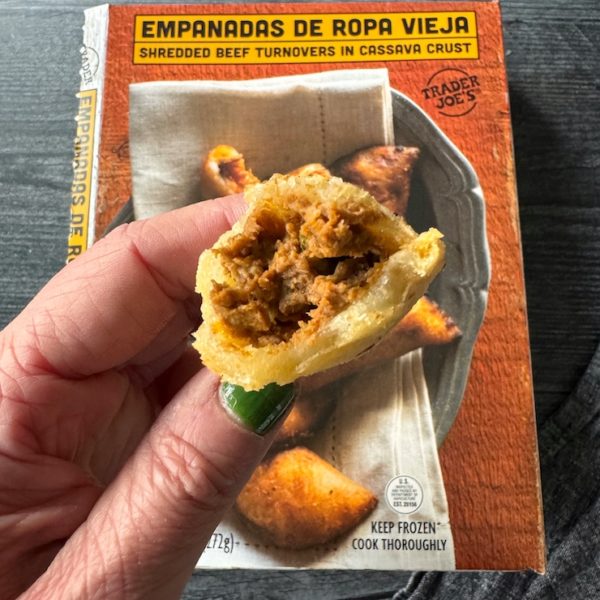 Meat filled interior of an empanada broken in half.