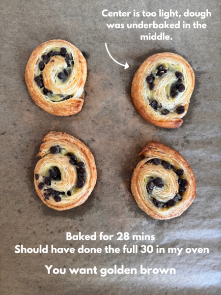 Trader Joe's Chocolate Chip Mini Croissant Swirls just baked. Text notes center on one swirl is too light, dough was underbaked in the middle.
