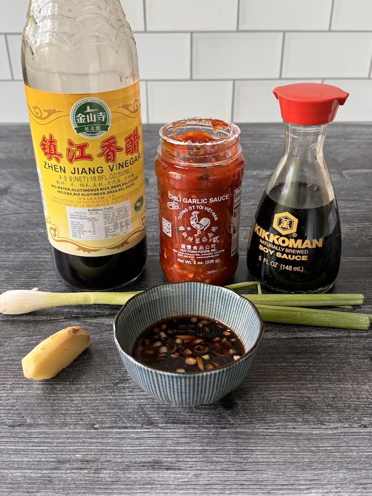 Steamed Dumpling Dipping sauce ingredients: Black vinegar, chili garlic sauce, soy sauce, green onion, ginger and the little bowl of it all mixed together.