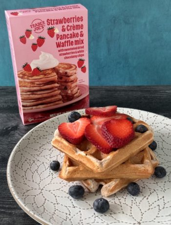 Trader Joe's Strawberries & Creme Pancake and Waffle mix with a plate of 3 stacked waffles topped with strawberries and blueberries