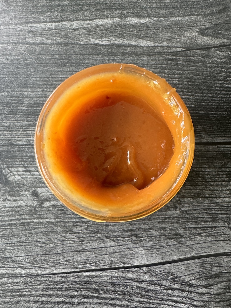 Trader Joe's Yuzu Miso top view looking down into an open jar. The yuzu miso is a orangish-brown color.