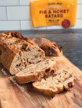 Trader Joe's Fig and Honey Batard with two cut slices on a wooden board.