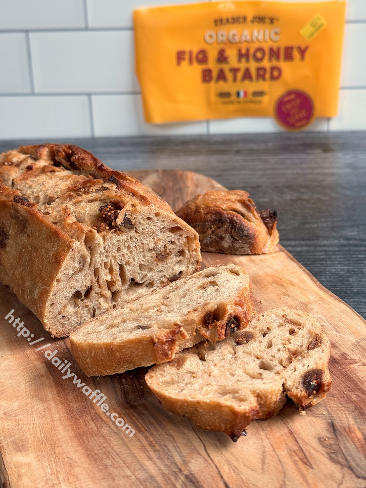 Trader Joe's Fig and Honey Batard with two cut slices on a wooden board.