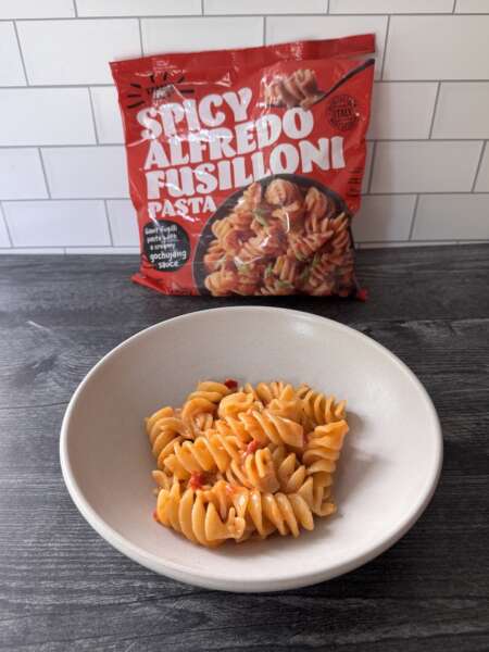 Trader Joe's Spicy Alfredo Fusilloni in a white bowl with the bag in the background