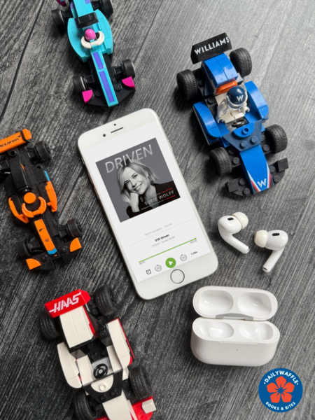 Driven by Susie Wolff audiobook cover shown on an iPhone surrounded by Lego F1 cars from F1 Academy, McLaren, Williams and Haas. A set of earbuds and their case are in the bottom right.