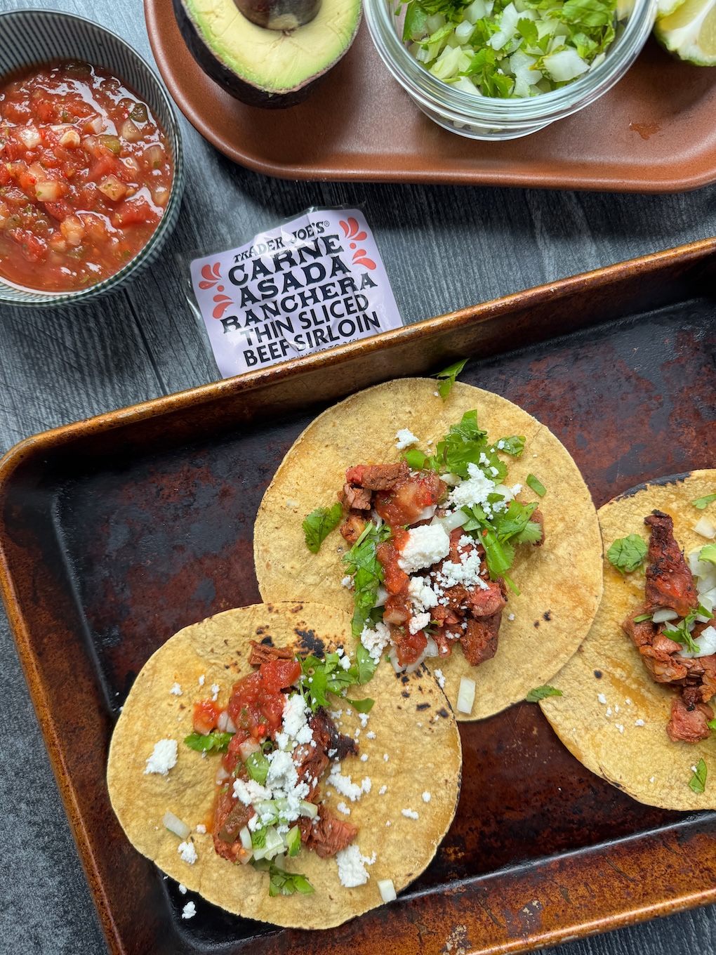 Trader Joe's Carne Asada tacos served on a quarter sheet pan with product label in the center of the image